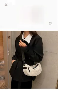 Close-up of white quilted saddle bag with adjustable black strap worn over a black coat