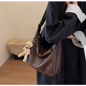 Detalle de bolso hobo marrón oscuro vintage con un bonito colgante de oso de punto