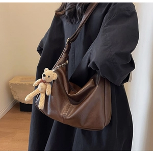 Detalle del bolso tote de cuero suave marrón con colgante de oso en una mujer modelo