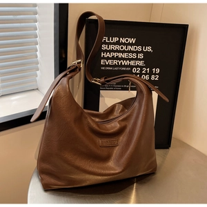 Détails de texture d'un sac cabas marron en similicuir avec logo et boucle dorée chic