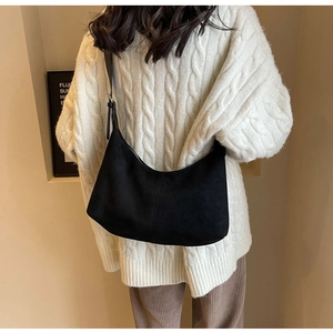 Detail of black frosted crescent shoulder bag paired with a white knit sweater
