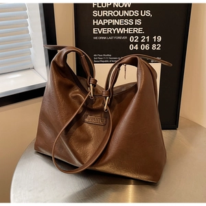 Détail du grand sac cabas marron foncé montrant le logo BANATU sur une table en métal