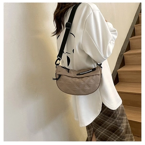 Khaki quilted half-moon crossbody bag shown with adjustable black wide strap on model