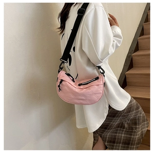 Detailed view of pink quilted crescent bag with adjustable wide fabric shoulder strap