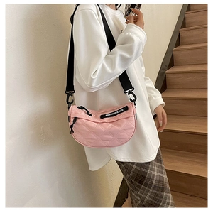 Detailed macro view of pink quilted nylon crossbody bag with chic fashion woven label