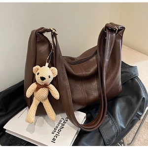 Detalle de bolso tote de cuero PU marrón con colgante de oso tejido y cierre de cremallera