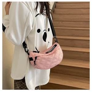 Detailed side view of pink quilted crescent saddle bag with black nylon strap on a model