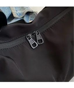 Detail of smooth black metal dual zippers on a durable nylon canvas crossbody bag