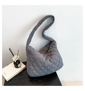 Detailed view of grey corduroy quilted hobo bag in minimalist interior setting