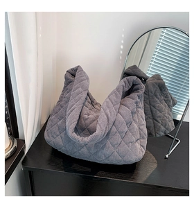 Detail of grey quilted corduroy shoulder bag showing texture on a dark wood surface