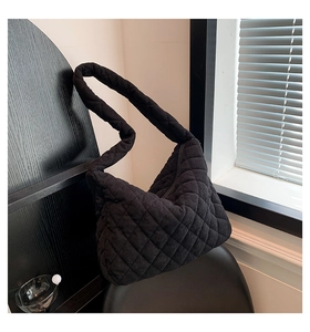 Detail of black quilted corduroy tote bag showing soft texture and wide shoulder strap