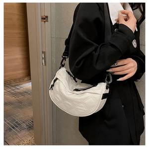Detail view of white quilted half-moon shoulder bag with black adjustable nylon strap