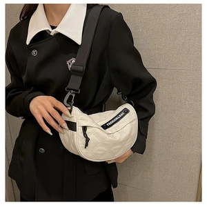 Detail view of white quilted crescent bag featuring adjustable black strap and fashion logo