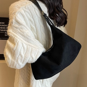 Minimalist matte black hobo shoulder bag with adjustable strap in a lifestyle scene