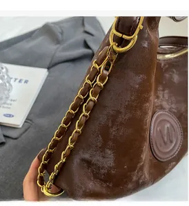 Detail of dark brown vintage tote featuring textured leather and gold metal chain strap