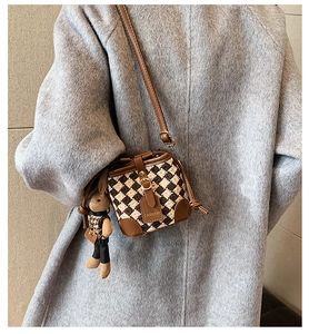 Detail of small plaid crossbody bucket bag with brown leather trim and rabbit charm