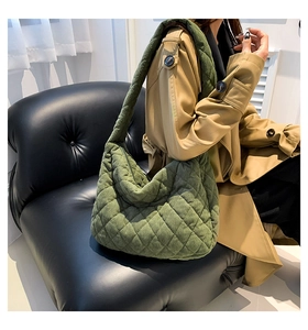 Detailed texture of dark green quilted corduroy fabric on a stylish tote shoulder bag