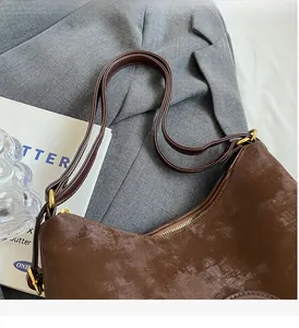 Detail of brown suede tote bag with leather handle and antique gold metal ring attachment