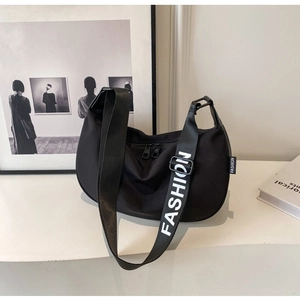Close-up of black nylon crescent bag with branded fashion wide strap on white stand