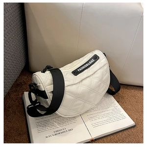 Detail of white quilted half-moon bag with black shoulder strap and fashion label