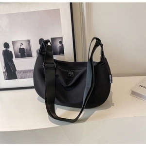 Detail of minimalist black nylon crescent bag featuring adjustable strap and fashion label