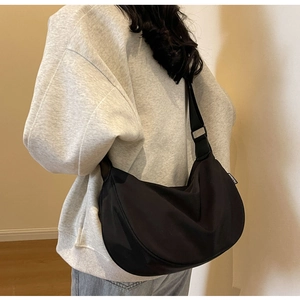 Detail of black nylon crescent bag with adjustable strap and Fashion label on the side