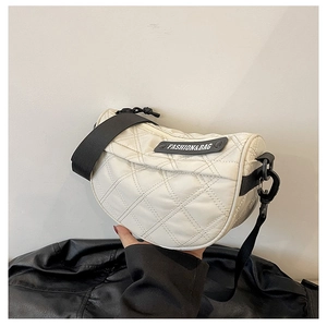 Close-up of cream crescent crossbody bag featuring quilted lattice pattern and logo patch