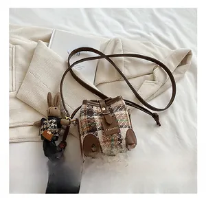 Detail showing vintage plaid fabric, brown leather trim, and cute bunny charm on the bag