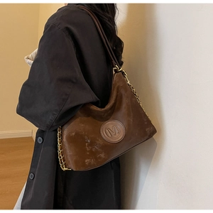 Detail view of the brown matte hobo bag with M-logo embossing and metal chain strap