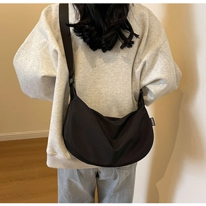 Detail of black crescent crossbody bag with FASHION label and wide nylon shoulder strap