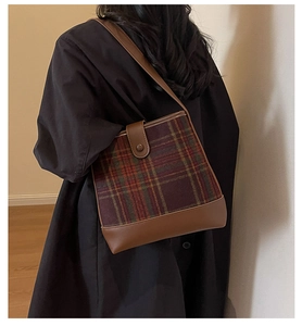 Vue latérale d'un sac seau à carreaux vintage avec lanières en cuir marron et bouton pression