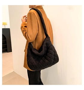 Detail of black quilted corduroy hobo bag showing texture and crossbody strap on model