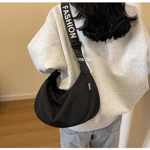 Detailed view of black nylon crescent bag featuring a wide FASHION lettered shoulder strap