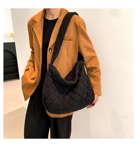 Detail of black quilted hobo bag in soft corduroy fabric with wide shoulder strap