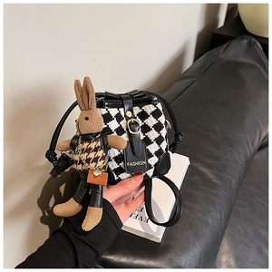 Detail of houndstooth bucket bag featuring a leather tag and cute knitted rabbit charm