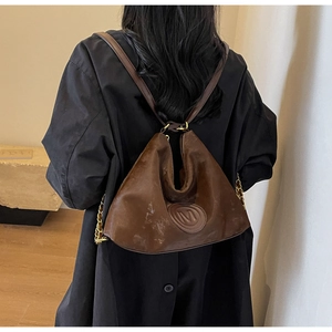 Close-up of brown faux leather tote bag with embossed M logo and gold chain strap
