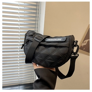 Detail of black quilted crescent bag featuring fashion tag and adjustable shoulder strap