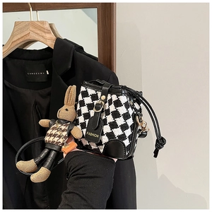 Detail of houndstooth bucket bag with drawstring closure and matching rabbit charm