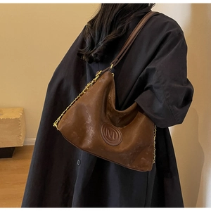 Close-up of vintage brown hobo bag with embossed M logo and gold chain strap detail