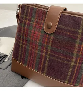 Gros plan du sac seau vintage à carreaux avec tissu texturé et détails en cuir marron