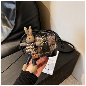 Detail of mini tweed bucket bag with a cute knitted bunny doll and leather trim