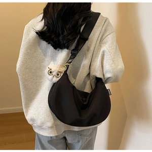 Detail of black nylon crescent crossbody bag featuring a cute white owl plush charm