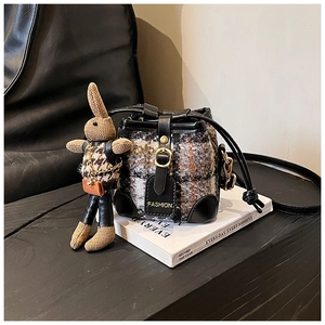 Detail of checkered tweed mini bucket bag with leather trim and brown rabbit charm