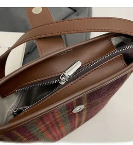 Détail du sac seau à carreaux rouge et vert montrant le zip argenté et la poche interne