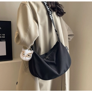 Detail of black nylon crescent bag with wide fashion strap and plush owl charm
