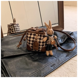 Detail of mini checkered bucket bag with leather base and cute rabbit plush charm