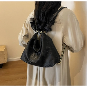 Detail of black suede backpack with embossed M logo and decorative gold chain strap