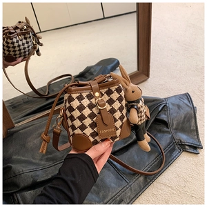Close-up of vintage mini bucket bag in brown houndstooth fabric with plush bunny charm