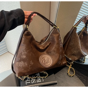 Close-up of retro brown leather tote with M logo and gold chain shoulder strap