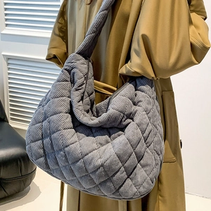 Gray corduroy quilted hobo tote bag with spacious interior shown on model in khaki coat